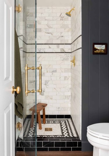 traditional shower fixtures in black and white bathroom with brass fixtures