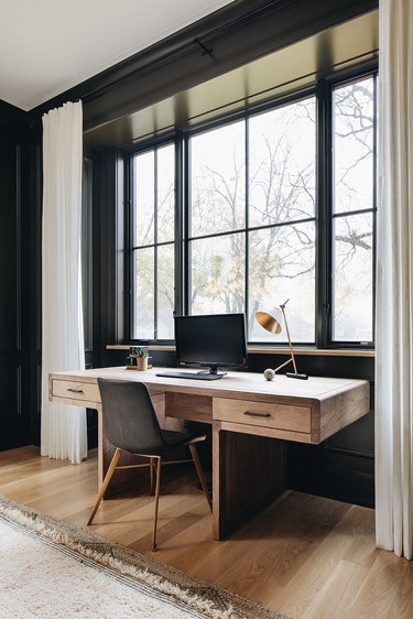 black home office with desk in front of windows