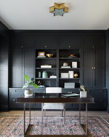 black home office with light wood floors, desk in the center of the room with a star-shaped pendant hanging above