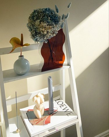 a shelf decorated with candles, coffee table books, and vaces