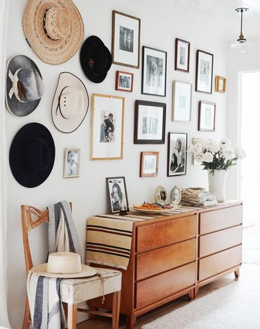 Hallway Gallery Wall Ideas with credenza, photos, prints, hats, chair, flowers.