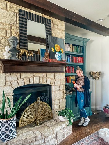 Sarisa Munoz of The Indigo Leopard Home standing in front of stone fireplace