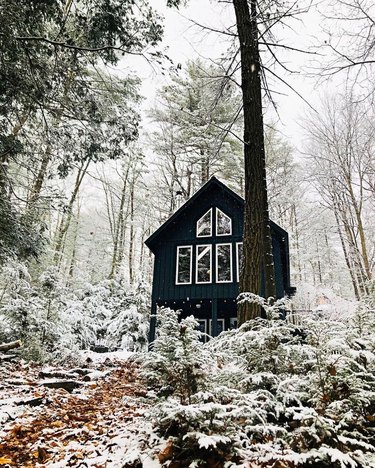 snowy outdoor scene with view of a black a-frame house