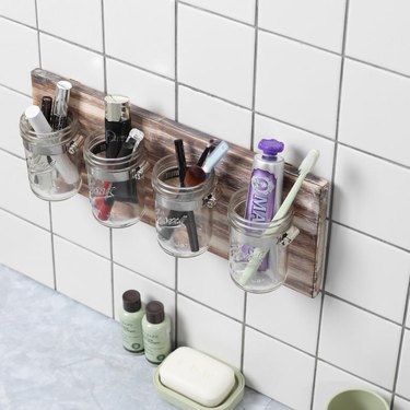 mason jar for bathroom storage mounted to white tile wall