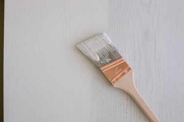 Painting second coat of light gray milk paint onto desk