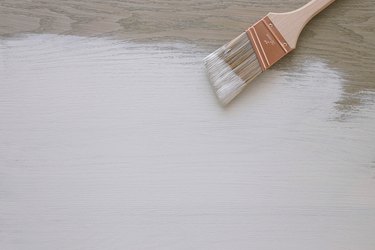 paintbrush and partially painted wood surface