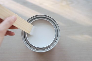 Stirring paint in can with a wood paint stick