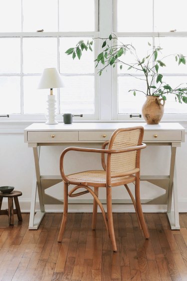 Home office desk painted with light gray milk paint in front of window with lamp and vase