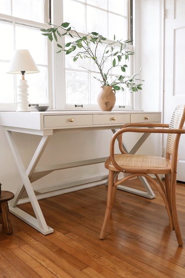 Home office desk painted with light gray milk paint in front of window with lamp and vase