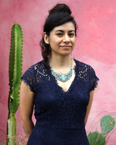 person standing near pink wall and cactus