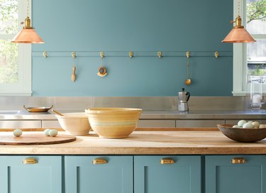kitchen with teal wall and cabinets and bowls on counter
