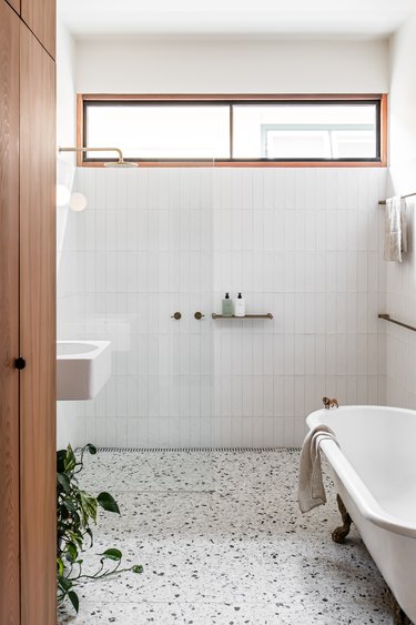 white modern bathroom with terrzzo floors and a clawfoot tub next to a standing shower