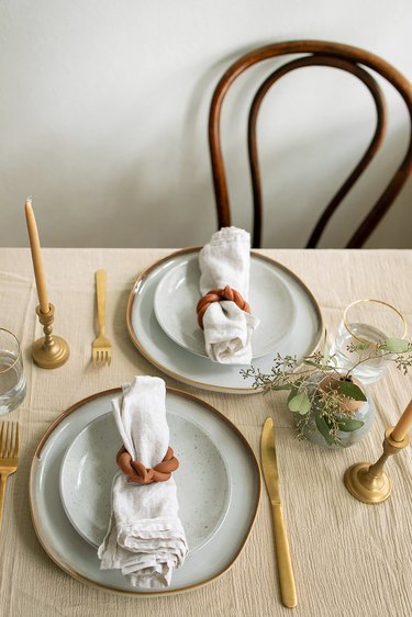 Table set with two plates and linen napkins inside DIY twisted clay napkin rings