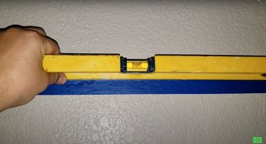 blue masking tape with blue markings on wall with level