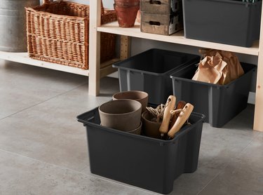 Black plastic storage containers in garage with outdoor essentials