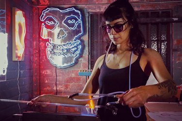 Neon artist Leticia Maldonado in her art studio with skull art in the background