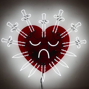 Neon art by Dani Bonnet of red heart with several swords piercing it.