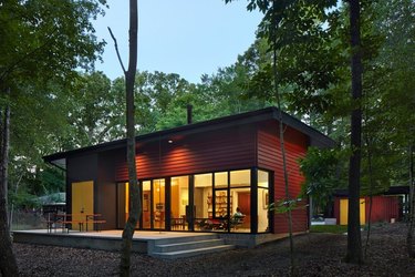 red modular home in a forest with eco-friendly home design