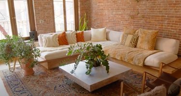 living room space with couch and plants and brick wall