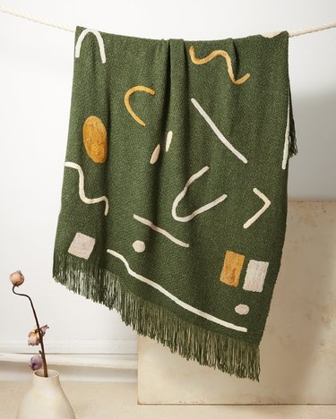 sustainable home decor with green patterned blanket hanging
