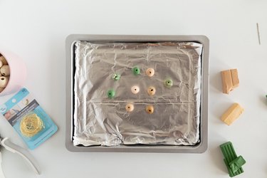 Baking sheet with foil and beads of clay to be baked