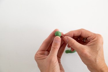 Sticking a needle through a ball of green clay