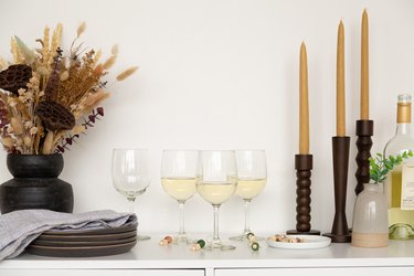 Wine classes on counter with candles and black vase with dried flowers