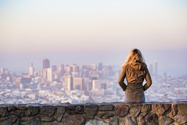 woman on rock platform looking at san francisco cityscape