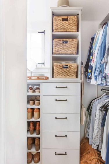 Walk-in closet designed by Emily Henderson with white cabinetry, shoe shelves, and light wicker baskets.