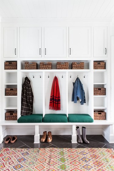 mudroom storage with white cabinets, slate floor and eclectic rug