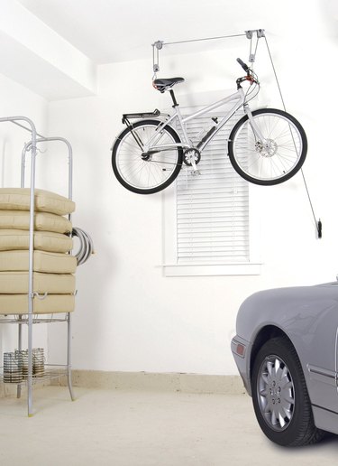 bike storage hanging from a pulley system in a garage with a car