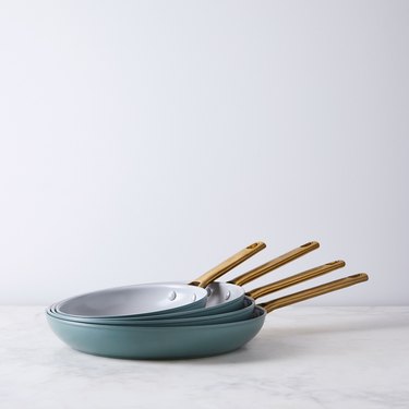 Four nested teal ceramic frying pans