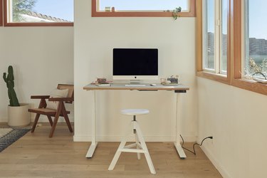 standing desk near windows and white stool