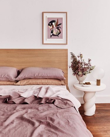bed threads Lavender, Terracotta, and Rosewater bedding with wood headboard and white side table