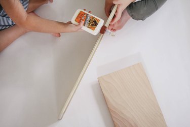 Two kids gluing wood boards together