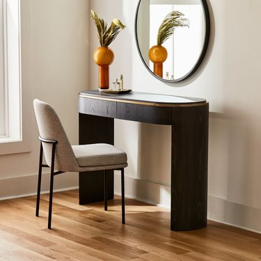 chair in front of console table and mirror