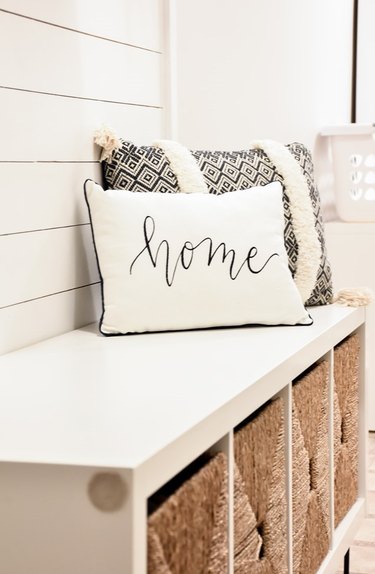 DIY storage bench with white top and baskets with throw pillows