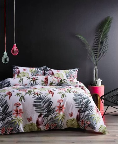 bedroom with black wall and bedding with tropical flowers and birds pattern