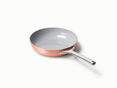 Peach frying pan with gray interior and stainless steel handle