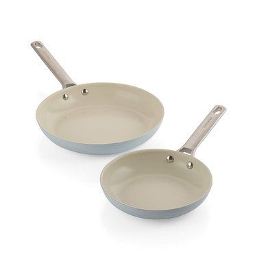 Two different sized gray frying pans with beige interior and handle