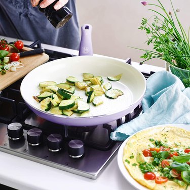 Lavender frying pan with white interior cooking zucchini slices