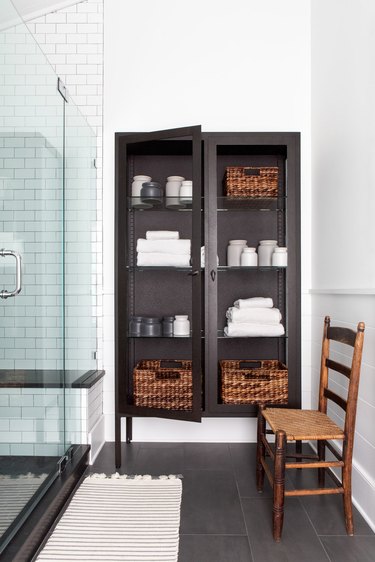 black freestanding cabinet next to shower for bathroom shelving