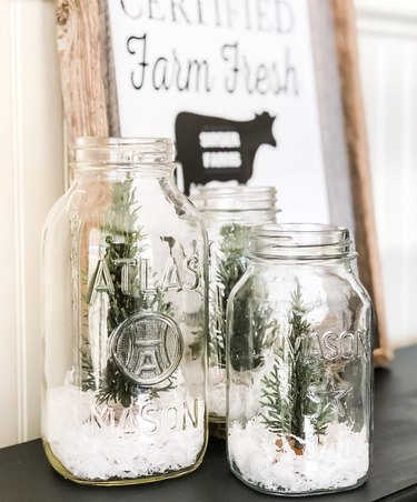 two Mason jars with faux snow and trees