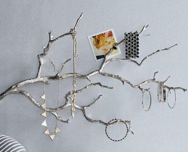 Earring Storage with Silver finished branch on wall with jewelry hanging.