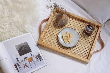 DIY cane webbing tray on bed with wine, crackers and magazine