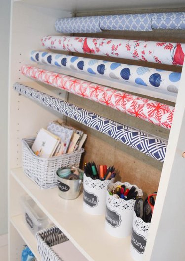wrapping paper storage idea with stacked reams and cups for pens