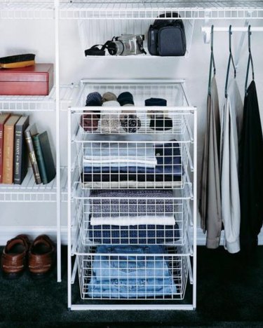 Closet organizer with white wire drawer unit, clothes, shoes.
