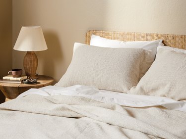 cream bedding with natural woven headboard and bedside table
