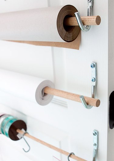 wrapping paper storage idea on back of door with wooden dowels