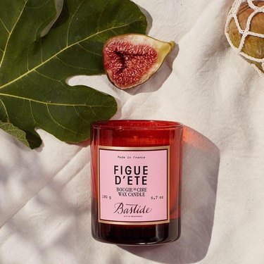 Bastide’s Figue d’Ete Candle next to fig and green leaf